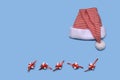 Santa`s striped hat, laid out on a blue background. Below are white papered gifts and bandaged red ribbon with a bow Royalty Free Stock Photo