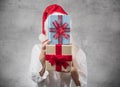 Santa woman holding christmas gifts and covering his face, isolated on gray background. Happy young girl wearing red santa hat and Royalty Free Stock Photo