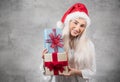 Santa woman holding christmas gifts isolated on gray background. Happy young girl wearing red santa hat and holding present box Royalty Free Stock Photo