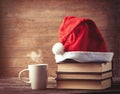 Santas hat over books near hot cup of coffee or tea Royalty Free Stock Photo