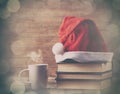 Santas hat over books near hot cup of coffee or tea Royalty Free Stock Photo