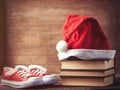 Santas hat over books near red gumshoes Royalty Free Stock Photo