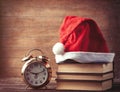 Santas hat over books near retro alarm clock Royalty Free Stock Photo