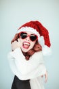 Santas little helper. Beautiful happy young woman with a santa claus hat, perfect make up, red lipstick, and heart shape sun glass Royalty Free Stock Photo