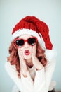 Santas little helper. Beautiful happy young woman with a santa claus hat, perfect make up, red lipstick, and heart shape sun glass Royalty Free Stock Photo