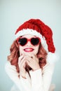 Santas little helper. Beautiful happy young woman with a santa claus hat, perfect make up, red lipstick, and heart shape sun glass Royalty Free Stock Photo