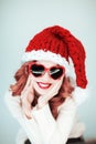 Santas little helper. Beautiful happy young woman with a santa claus hat, perfect make up, red lipstick, and heart shape sun glass Royalty Free Stock Photo