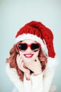 Santas little helper. Beautiful happy young woman with a santa claus hat, perfect make up, red lipstick, and heart shape sun glass Royalty Free Stock Photo