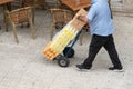 Man carrying drinks on hand cart on sidewalk. Working or transportation concept