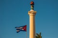 SANTIAGO DE CUBA, CUBA: Column of Liberty on Plaza de Marte square. Cuba flag develops on the background of the sky