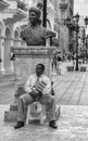Santo Domingo, Dominican Republic. A man sitting at the base of Bartolomeo Colon statue, located in Conde street. b/n version