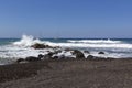 Santorini, beautiful black beach of Vlychada illuminated by the sun. Beautiful sea with high long waves breaking on black lava Royalty Free Stock Photo