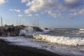 Santorini, beautiful black beach Vlychada illuminated by the sun. Beautiful sea with high long waves that hit a built stone dam