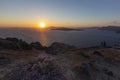 Santorini beautiful sunset over the Caldera, in front of a flowering heathland with stones on a cliff and in the background the Royalty Free Stock Photo