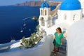 Santorini fashion woman climbing steps in Oia, famous white village with blue domes in Greece. Girl in green dress and sunglasses Royalty Free Stock Photo