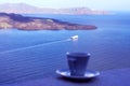 Santorini, Greece, April 2019. Strong delicious coffee in a white cup with a saucer against the backdrop of the sea and a floating