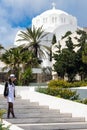 Santorini, Greece, April 2019. A young girl in a white dress and hat is photographed against the background of a white Greek churc Royalty Free Stock Photo