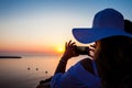 Young woman taking pictures of the beautiful sunset at the famous Caldera of Santorini Island in Royalty Free Stock Photo