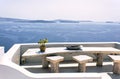 Santorini, Greece: A pot with flower or plant and a plate on a wooden table with wooden chair against beautiful sea ocean Royalty Free Stock Photo