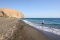 Angler catching fish at black sand beach of Perissa on the island of Santorini. Cyclades, Royalty Free Stock Photo