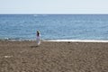 Tourist woman at black sand beach of Perissa on the island of Santorini. Cyclades, Greece Royalty Free Stock Photo