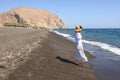 Tourist woman at black sand beach of Perissa on the island of Santorini. Cyclades, Greece Royalty Free Stock Photo