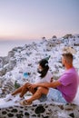 Santorini Greece, young couple on luxury vacation at the Island of Santorini watching sunrise by the blue dome church Royalty Free Stock Photo