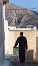 Greek Orthodox priest walking in picturesque Pyrgos village. Royalty Free Stock Photo