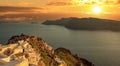 Santorini island, Greece. Oia caldera over Aegean sea, orange color cloudy sky, calm sea Royalty Free Stock Photo