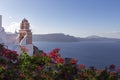 Santorini - Oia, a picturesque pink church tower built at the foot of a caldera, overgrown with pink oleander flowers. in the Royalty Free Stock Photo