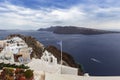 Santorini - Oia, view from the cliff to the caldera. On the cliff above the sea a white bell tower with the Greek flag and Greek Royalty Free Stock Photo