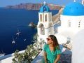 Santorini travel tourist woman visiting Oia, famous white village with blue domes in Greece. Girl in green dress and sunglasses l Royalty Free Stock Photo
