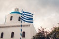 Santorini view of church with blue dome and greek flag in Oia, Greece. Tourism, traveling, summer vacation Royalty Free Stock Photo