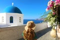 Santorini woman walking in beautiful street of Oia village with flowers and typical blue dome of the church, Santorini, Cyclades Royalty Free Stock Photo