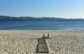 Sanxenxo, Spain. October 2018. Two women are resting and looking at the view on a beach boardwalk. Sunset, sunny day.