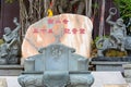 A stone monument with Chinese characters and figurines next to a Buddhist temple on the territory of Buddhist center Nanshan