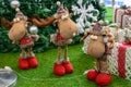 Christmas deers are standing under a Christmas tree with gifts in colorful hats and scarves in the red boots