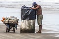 Man looks for aluminum cans for recycling in a trash bin