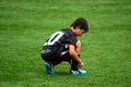 SAO PAULO, BRAZIL - SEPTEMBER 26, 2015: Young Boy tying boot on football field during rain