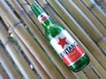 Sape Indonesia April 24, 2023 - Green Bottle of Bintang Beer, Indonesian Beer, on Bamboo Surface