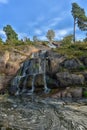 Sapokka Park in the city of Kotka in Finland. Waterfall with a cliff on the background of the lake, tourists on the bridge