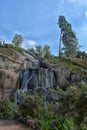 Sapokka Park in the city of Kotka in Finland. Waterfall with a cliff on the background of the lake, tourists on the bridge