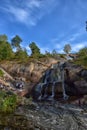 Sapokka Park in the city of Kotka in Finland. Waterfall with a cliff on the background of the lake, tourists on the bridge