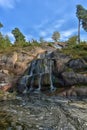 Sapokka Park in the city of Kotka in Finland. Waterfall with a cliff on the background of the lake, tourists on the bridge