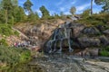 Sapokka Park in the city of Kotka in Finland. Waterfall with a cliff on the background of the lake, tourists on the bridge