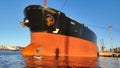 A sapsurfer swims in front of a huge tanker in the port of St. Petersburg.