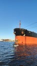 A sapsurfer swims in front of a huge tanker in the port of St. Petersburg.