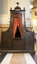 Old wooden confessional with red curtain