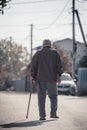 Saratov, Russia - 10.10.2021: An elderly pensioner man with a stick walks along the road. Lonely grandfather. Back view Royalty Free Stock Photo