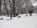 Saratov, Russia - Jan,2022: little girl rides on an ice slide next to older children in the city park where children